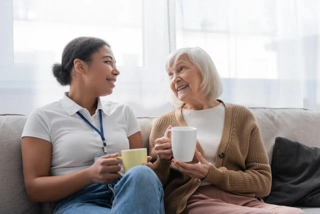 A support worker shares a cup of tea with an elderly lady