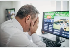 Man with head in hands in despair by computer screen with sports betting