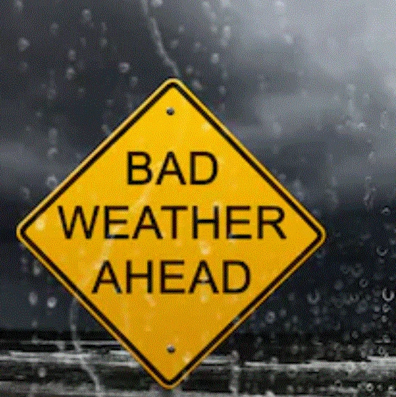 A yellow warning sign showing "bad weather ahead" in a rainy landscape