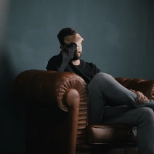 A photograph of a man with his head in his hand