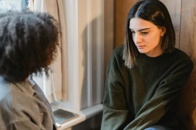 Two individuals sit looking contemplative
