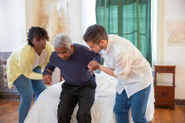 two support workers help a client to stand
