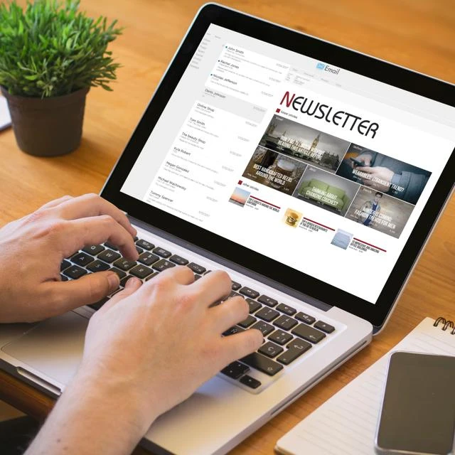 someone composing a newsletter on a laptop