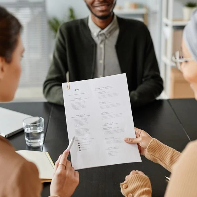 Two recruiting managers looking at an applicant's CV in an interview setting.