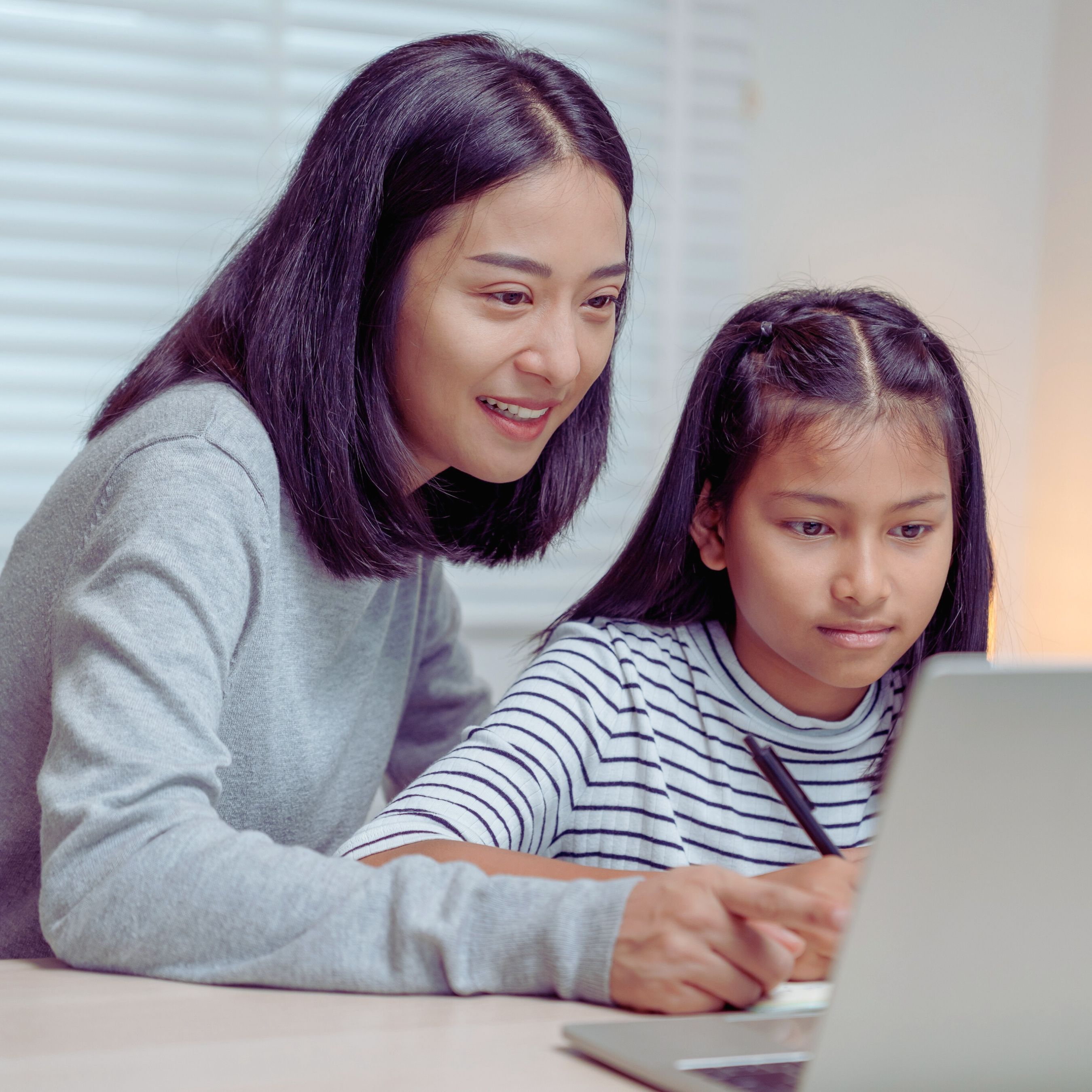 A mother and daughter share a laptop