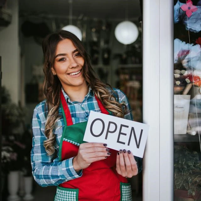 woman holding an Open sign at a florist shop