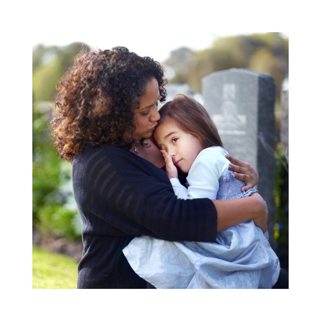 A mother comforts her child by a gravestone