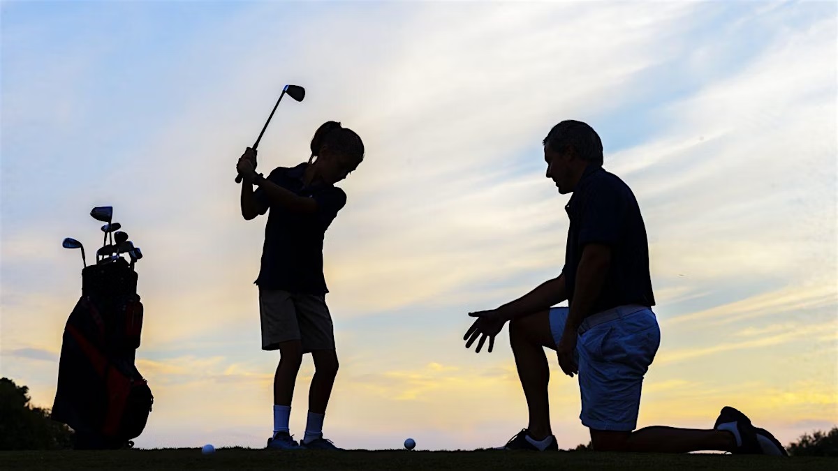 an adult shows a child how to swing a golf club