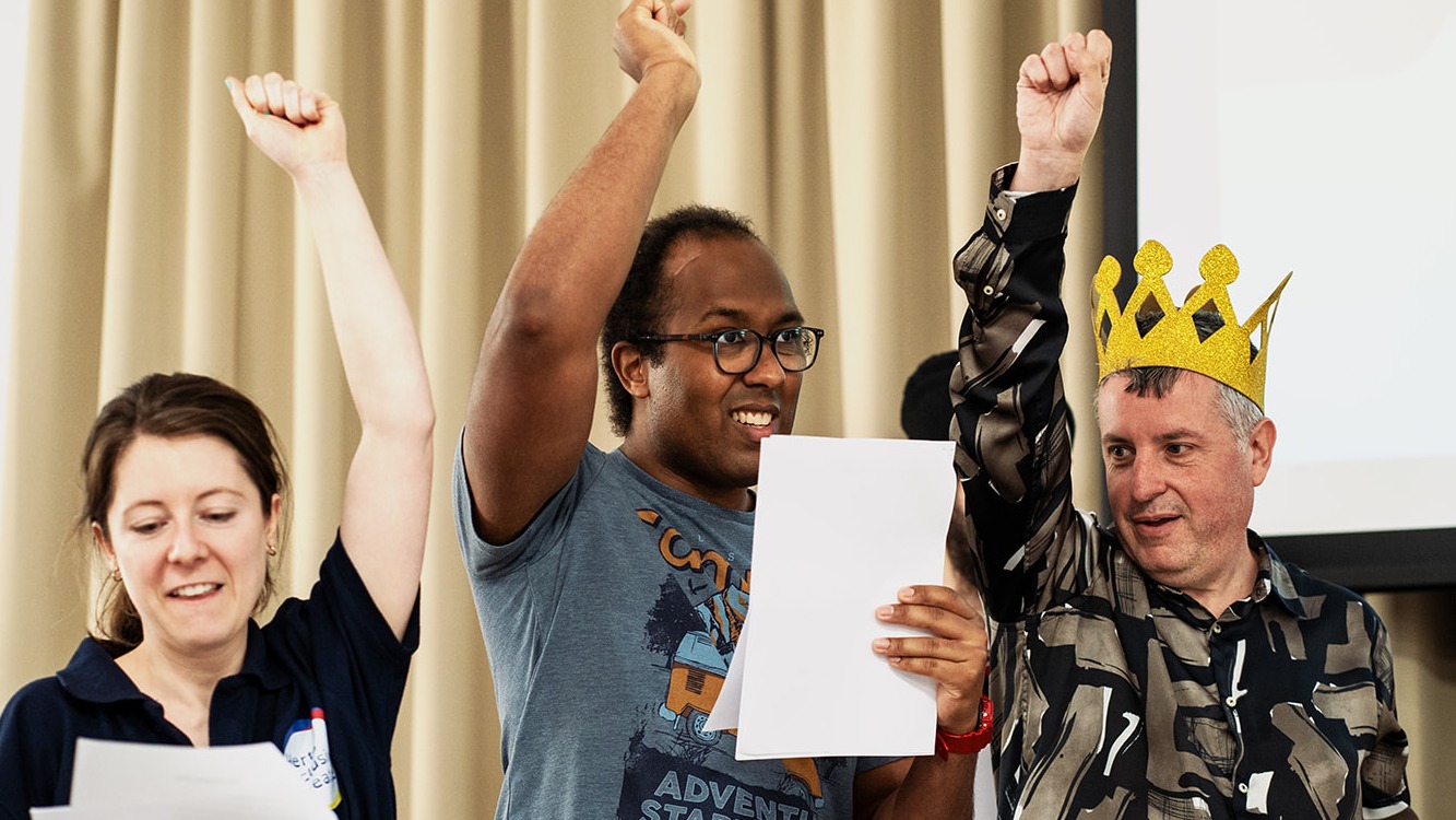 Photo of 3 adults acting with script