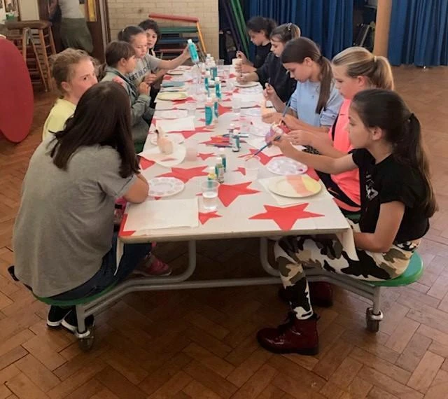 A group of girls sit together doing arts and crafts