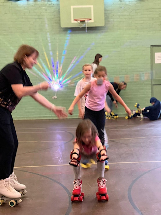 Children roller skating with disco lights in a large hall