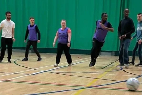 young adults playing futsal in a sports hall